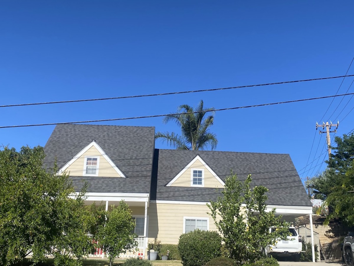 A two-story house with twin gabled dormers finished in charcoal architectural shingle.