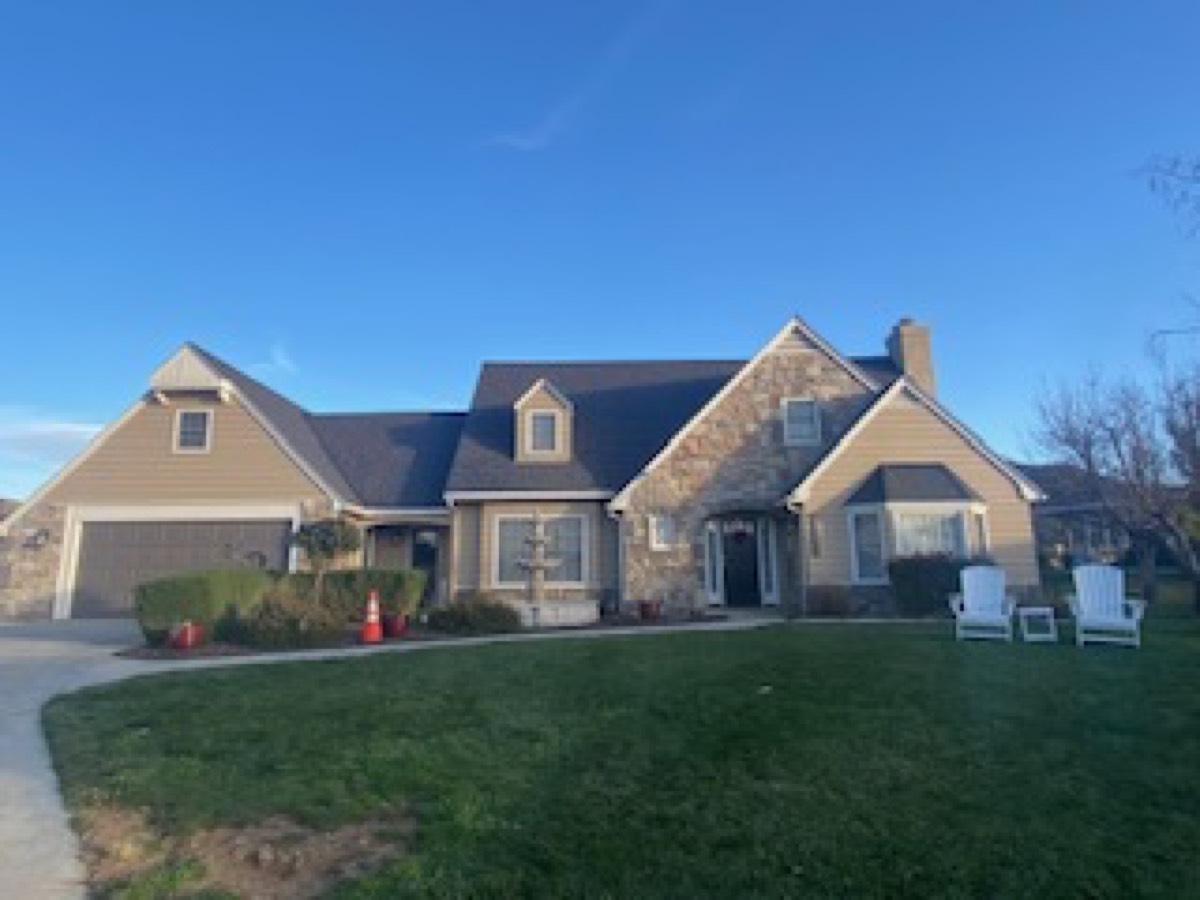 A large stone and shingle two-story home with multiple gables and an attached garage.
